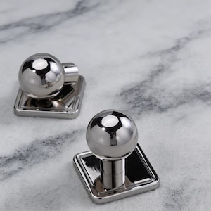 May include: A white ceramic mug with a black handle and the text "But first, coffee" in a black, handwritten-style font. The mug is on a white surface.