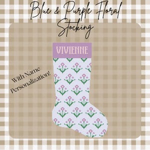 May include: A personalized Christmas stocking with a blue and purple floral design. The stocking features the name "VIVIENNE" in a lavender band at the top. The background is a light blue with a repeating pattern of pink flowers and green leaves. Text reads "With Name Personalization!"