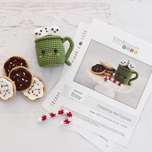 K&ouml;nnte beinhalten: H&auml;kelanleitung f&uuml;r eine Tasse hei&szlig;e Schokolade zu Weihnachten mit Marshmallows, Zuckerstangen und Keksen. Die Anleitung ist einfach zu befolgen und enth&auml;lt Anweisungen zum Herstellen der Tasse, Marshmallows, Zuckerstangen und Kekse. Die Anleitung ist in englischer Sprache verfasst und enth&auml;lt eine Maschenprobe von 18 Maschen pro 10 cm mit einer H&auml;kelnadel von 3,75 mm.