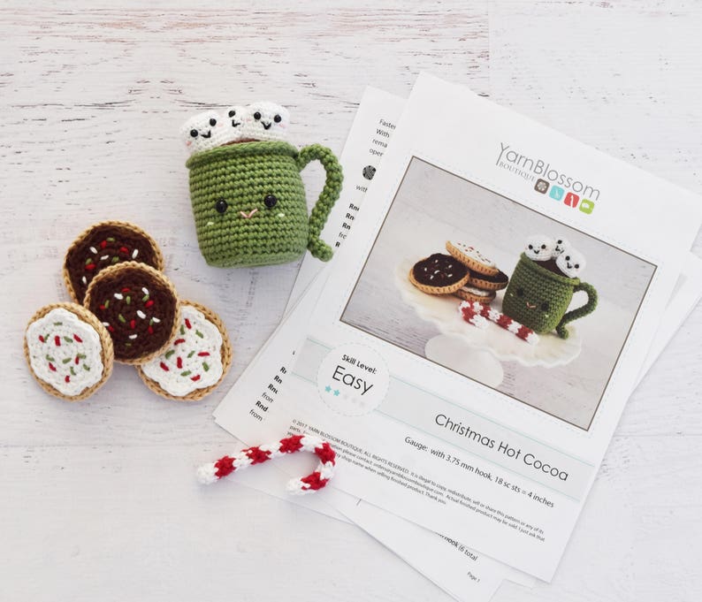 K&ouml;nnte beinhalten: H&auml;kelanleitung f&uuml;r eine Tasse hei&szlig;e Schokolade zu Weihnachten mit Marshmallows, Zuckerstangen und Keksen. Die Anleitung ist einfach zu befolgen und enth&auml;lt Anweisungen zum Herstellen der Tasse, Marshmallows, Zuckerstangen und Kekse. Die Anleitung ist in englischer Sprache verfasst und enth&auml;lt eine Maschenprobe von 18 Maschen pro 10 cm mit einer H&auml;kelnadel von 3,75 mm.