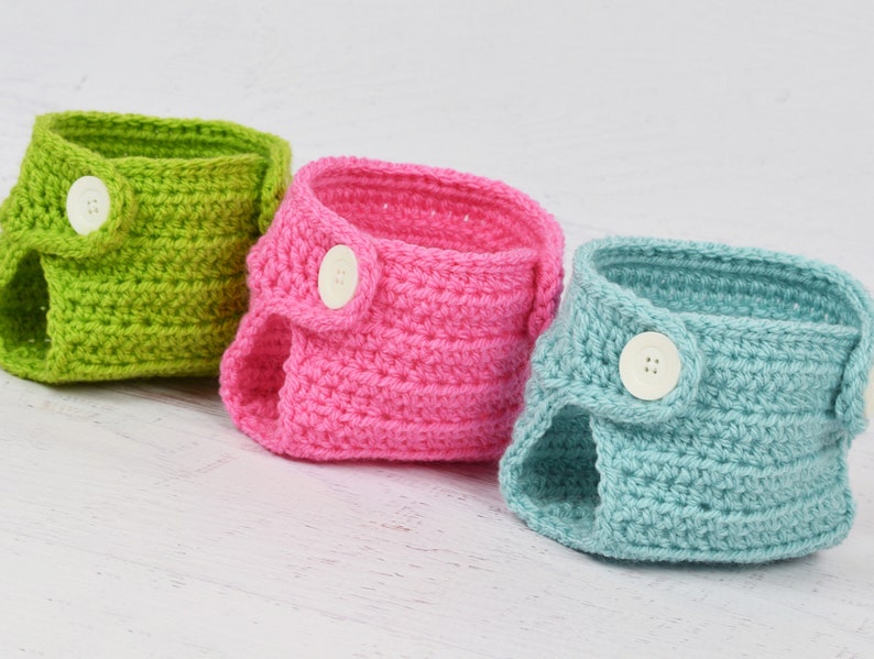May include: Three crocheted baby diaper covers in green, pink, and blue with white buttons.