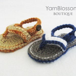 May include: Two pairs of crocheted baby sandals. One pair is beige with orange accents and the other is gray with white and blue accents.