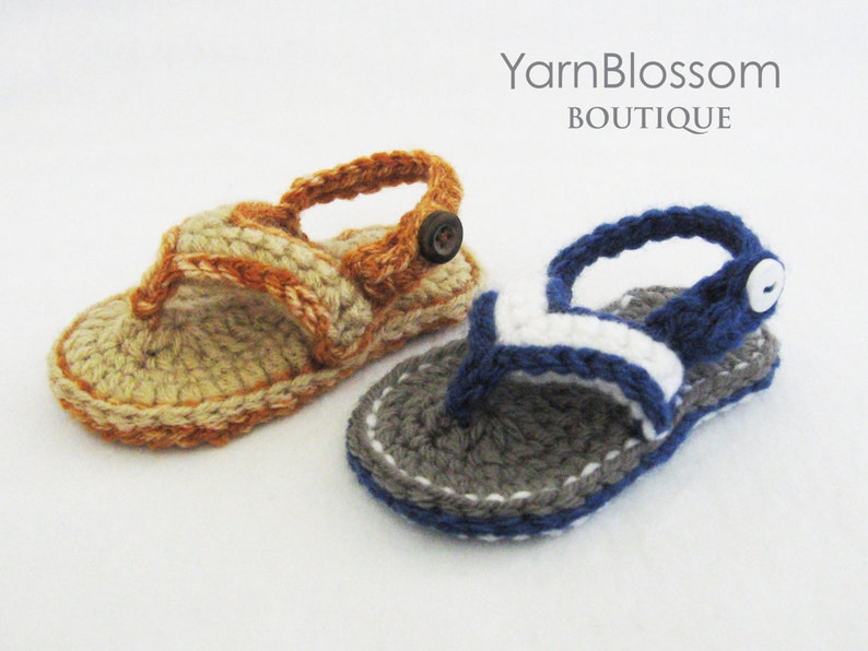 May include: Two pairs of crocheted baby sandals. One pair is beige with orange accents and the other is gray with white and blue accents.