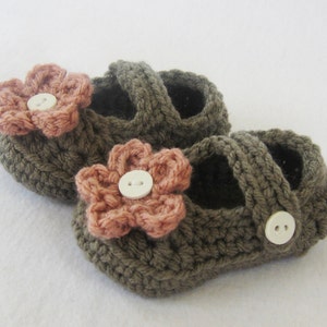 May include: A pair of brown crocheted baby shoes with pink flower embellishments and white buttons.
