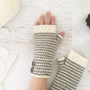 May include: A pair of fingerless gloves with a striped pattern in beige and white. The gloves have a button detail on the wrist.