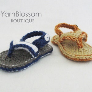 May include: Two pairs of crocheted sandals, one in gray and blue with a white stripe and a white button, and the other in tan and orange. The sandals are on a white background.