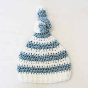 May include: A blue and white striped crocheted hat with a knotted top.