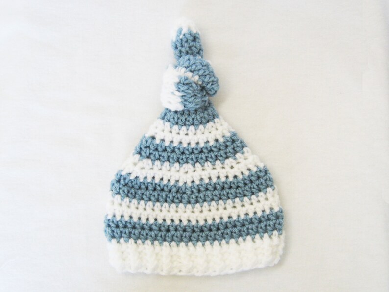 May include: A blue and white striped crocheted hat with a knotted top.