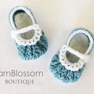 May include: A pair of crocheted baby shoes in blue and white. The shoes have a white crocheted trim around the top and a white strap with a button.