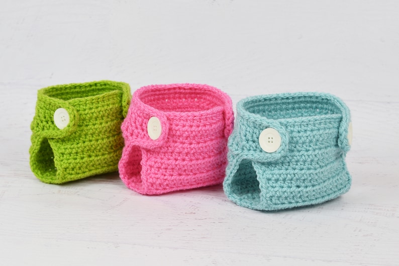 May include: Three crocheted baby diaper covers in green, pink, and blue with white buttons.