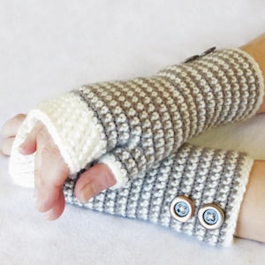 May include: A pair of gray and white fingerless gloves with buttons. The gloves are crocheted and have a striped pattern.