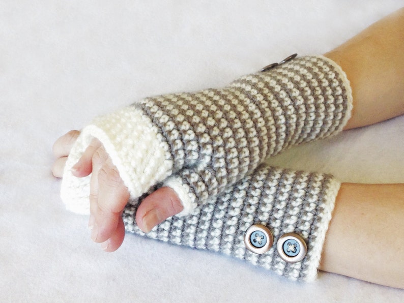 May include: A pair of gray and white fingerless gloves with buttons. The gloves are crocheted and have a striped pattern.