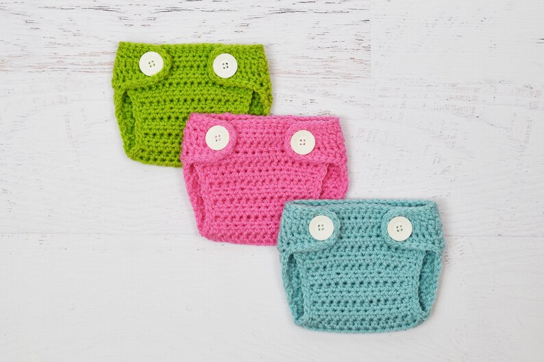 May include: Three crocheted baby diaper covers in green, pink, and blue with white buttons.