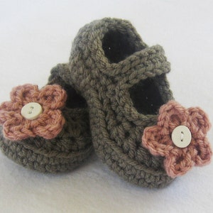 May include: A pair of brown crocheted baby shoes with pink flower embellishments and white buttons.