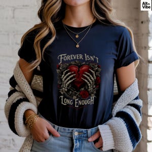 Puede incluir: Camiseta azul marino con la frase "Forever Isn't Long Enough". El diseño presenta un corazón rojo sostenido por manos esqueléticas, rodeado de rosas. La camiseta tiene cuello redondo.