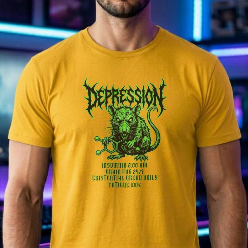 Puede incluir: Camiseta amarilla mostaza con un gr&aacute;fico verde. El gr&aacute;fico presenta la palabra "DEPRESSION" en una fuente puntiaguda sobre una rata verde que sostiene una estructura molecular. Debajo de la rata est&aacute;n las palabras "INSOMNIO 2:00 AM NIEBLA CEREBRAL 24/7 ANGUSTIA EXISTENCIAL DIARIA FATIGA 100%."