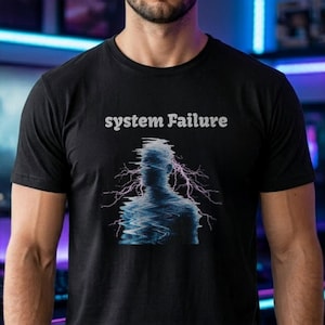 Puede incluir: Camiseta negra con el texto "system Failure" en blanco. La camiseta presenta un gráfico de la silueta de una persona con un efecto de fallo y rayos rosas que emanan de la cabeza.