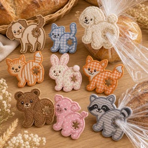 May include: A collection of nine embroidered animal-shaped bread clips, including a dog, cat, rabbit, fox, bear, pig, and raccoon. Each clip features a cutout hole for securing plastic bags, with various patterns like gingham, stripes, and polka dots.