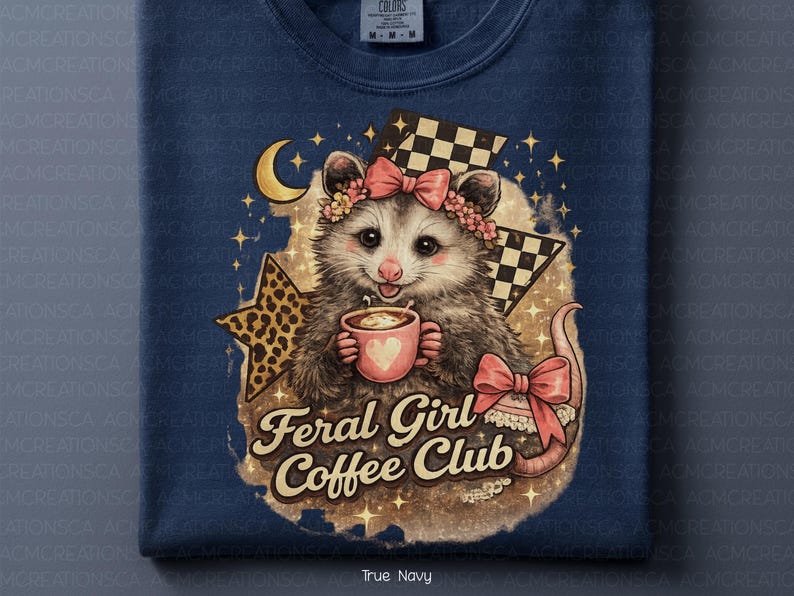 May include: Navy blue sweatshirt featuring a possum with a floral crown and bow, holding a coffee cup with a heart. The design includes a crescent moon, stars, and the text "Feral Girl Coffee Club".