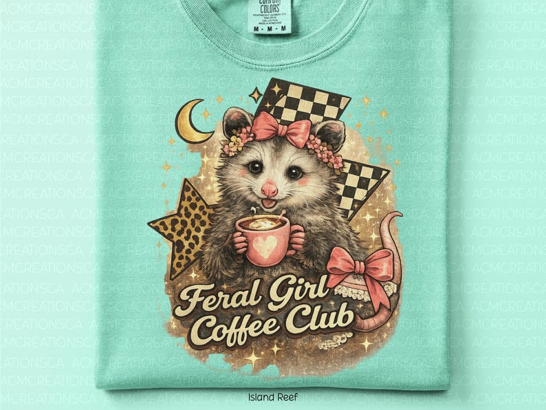 May include: A light turquoise t-shirt featuring a possum illustration holding a coffee cup. The possum wears a floral crown and a pink bow. The text "Feral Girl Coffee Club" is below the possum. A crescent moon, stars, and checkered flags complete the design.