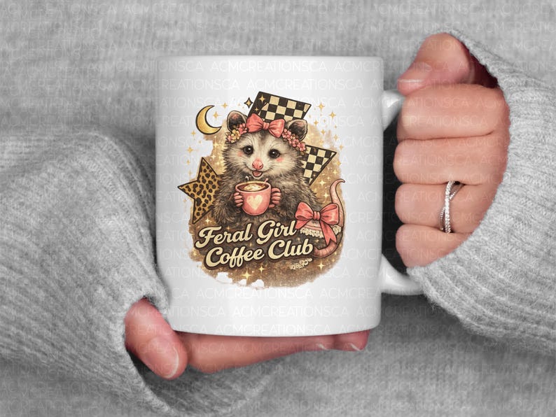 May include: White ceramic mug featuring a whimsical illustration of an opossum holding a coffee cup. The opossum wears a pink bow and is surrounded by stars, a crescent moon, and the text "Feral Girl Coffee Club."