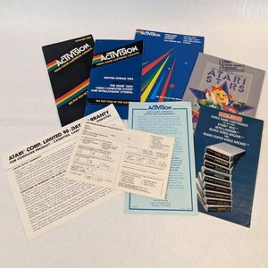 May include: A collection of vintage video game paper ephemera including Activision catalogs from 1982 and 1983, an Atari Stars catalog, a Coleco video game cartridge brochure, and two Atari Corp. limited 90-day warranty and registration forms.