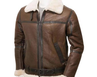 Puede incluir: Chaqueta de cuero marrón con cuello y forro de borrego blanco. La chaqueta tiene cremallera frontal, cinturón en la cintura y ribetes negros. La chaqueta se exhibe en un maniquí.