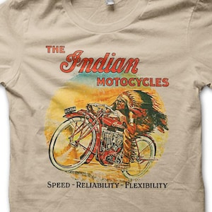 May include: Tan t-shirt featuring a vintage illustration of an Indian motorcycle. The graphic includes a rider in a headdress on a red motorcycle, with text that reads "The Indian Motorcycles" and "Speed - Reliability - Flexibility."