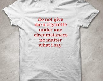 Könnte beinhalten: Weißes T-Shirt mit Rundhalsausschnitt und kurzen Ärmeln. Der rote Text auf dem Shirt lautet: "do not give me a cigarette under any circumstances no matter what i say."