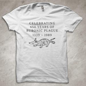 Könnte beinhalten: Weißes T-Shirt mit dem Text "CELEBRATING 650 YEARS OF BUBONIC PLAGUE 1339 - 1989" und einer schwarz-weißen Rattenillustration. Das T-Shirt hat kurze Ärmel und einen Rundhalsausschnitt. Ein humorvolles Design.