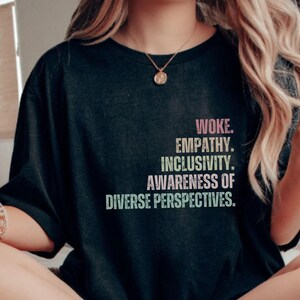May include: A black t-shirt with the text "Woke. Empathy. Inclusivity. Awareness of Diverse Perspectives." printed in rainbow colors.