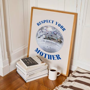 May include: A framed rectangular wall art print featuring a central silver disco ball graphic. The text "RESPECT YOUR MOTHER" is printed in bold blue capital letters, with "RESPECT YOUR" arched above and "MOTHER" positioned below the disco ball.