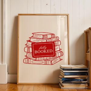 Può includere: Stampa incorniciata con un'illustrazione rossa di una pila di libri, con le parole "fully BOOKED" su un cartello rosso. La stampa è in una cornice di legno e su uno sfondo color crema. Una pila di libri è sul pavimento.