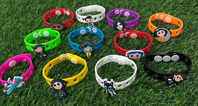 May include: A collection of colorful silicone bracelets with character charms. The bracelets are in various colors, including red, green, pink, yellow, blue, white, purple, orange, and black. Each bracelet features a different character design, perfect for fans of the animated movie.