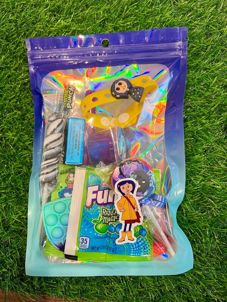 May include: A clear, iridescent bag filled with candy and small toys. Items include a yellow bracelet with a character design, a blue and green pop-it toy, and a lollipop. The bag contains a variety of colorful treats and a sticker.