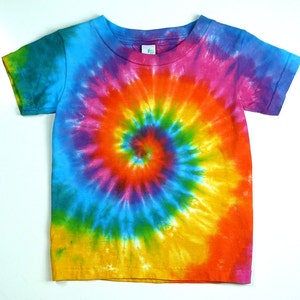 May include: A short-sleeved t-shirt featuring a vibrant tie-dye spiral pattern. The design incorporates a spectrum of colors including bright yellow, orange, red, pink, purple, blue, and green, radiating outward from the center of the garment.
