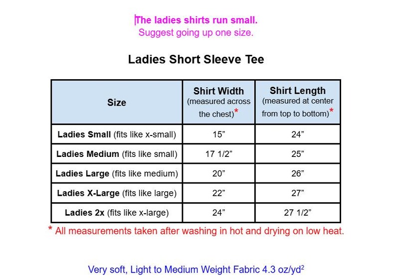 May include: A size chart for a short sleeve tee with text stating: The ladies shirts run small. Suggest going up one size. The table lists sizes from small to 2x with corresponding width and length measurements in inches from 15 to 27.5 inches.