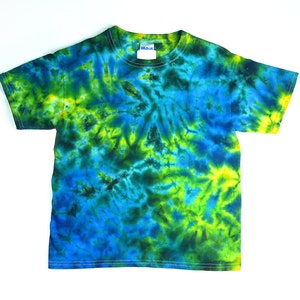 May include: A short-sleeve crew neck t-shirt featuring a vibrant tie-dye pattern in shades of bright blue, deep navy, and lime green. The garment has a standard fit with a round neckline and a white brand label visible inside the collar area.