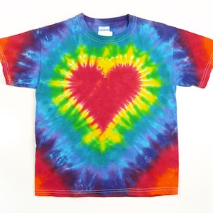 May include: A tie-dye t-shirt with a rainbow swirl pattern and a red heart in the centre. The shirt is made of a soft, comfortable cotton.