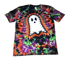 May include: A black tie-dye t-shirt with a white ghost design. The shirt has a colorful tie-dye pattern in shades of orange, green, purple, and black.