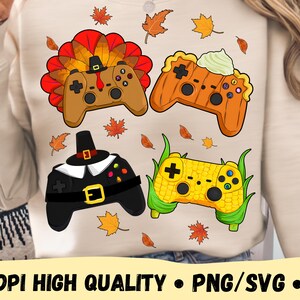 Op de afbeelding: Beige sweatshirt met vier gamecontroller-ontwerpen. De controllers zijn versierd als een kalkoen, pompoen, pelgrimshoed en maïskolf, met herfstbladeren verspreid. De tekst "300 DPI HIGH QUALITY • PNG/SVG • DIGITAL DOWNLOAD" staat onderaan.