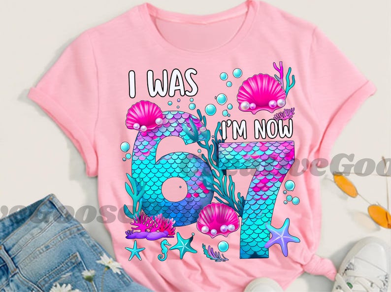 Puede incluir: Camiseta rosa con un dise&ntilde;o de sirena. El gr&aacute;fico presenta el texto "I WAS" encima de un n&uacute;mero grande "6" y "I'M NOW" encima de un "7", con escamas de sirena, conchas marinas y elementos acu&aacute;ticos.
