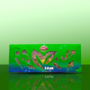 Puede incluir: Una caja verde de caramelos veganos con formas recortadas y la palabra "EGAN" en blanco. La caja tiene un degradado de azul y verde, con el logo "Candy 4U" en la esquina superior izquierda. Los caramelos son visibles a través de las formas recortadas.