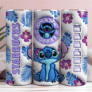 Op de afbeelding: Een witte beker met een blauw stripfiguur, Stitch, en de woorden "OHANA COFFEE" en "STARBUCKS". Het ontwerp bevat blauwe bladeren, paarse hibiscusbloemen en een drankaanpassingstabel.