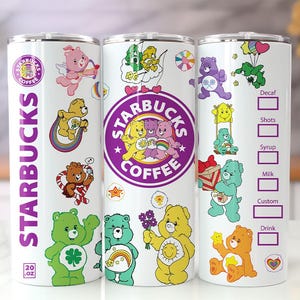 May include: A white 20 oz Starbucks tumbler featuring colorful Care Bears characters, including a pink bear with a bow and arrow, a yellow bear on a rainbow, and a green bear with a clover. The design includes the Starbucks logo and drink boxes.