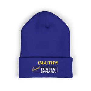 Puede incluir: Un gorro azul real con el texto "BLUTH'S Original FROZEN BANANA" en amarillo. El gorro es de punto, perfecto para mantener el calor. El texto está centrado en el borde doblado.