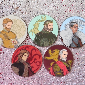 Puede incluir: Cinco pines redondos de esmalte de colores con personajes del popular programa de televisi&oacute;n Game of Thrones. Cada pin presenta un personaje diferente con el emblema de su casa. Los pines son perfectos para los fan&aacute;ticos del programa y son un gran regalo.