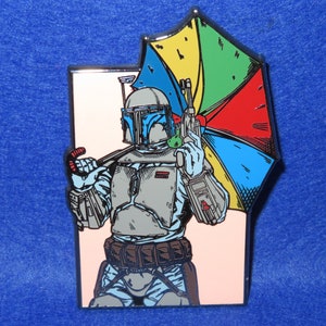 May include: A colorful enamel pin featuring a cartoon illustration of a Star Wars character, Boba Fett, holding a multi-colored umbrella. The pin is set against a white background with a silver border.