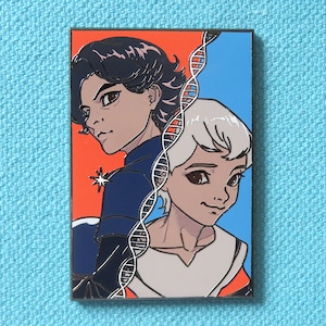 Pode incluir: Um broche de esmalte vermelho e azul com dois personagens de desenho animado. O personagem à esquerda tem cabelo escuro e veste uma jaqueta azul. O personagem à direita tem cabelo branco e veste uma camisa branca. Uma fita de DNA é visível entre os dois personagens.