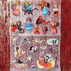Puede incluir: Un conjunto de 18 pegatinas coloridas con personajes de dibujos animados. Las pegatinas están en una hoja transparente con fondo blanco. Los personajes están en varias poses e incluyen sirenas, gatos y personas. Las pegatinas son perfectas para añadir un toque de fantasía a tu portátil, botella de agua o agenda.